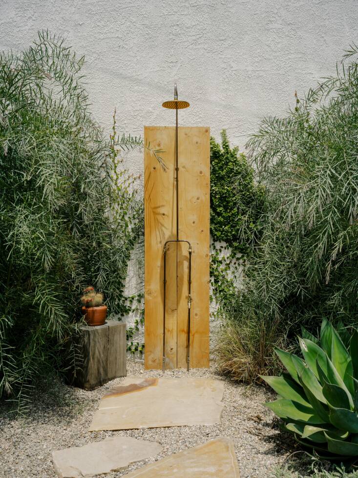 For the minimal outdoor shower, the idea was to feel immersed in plant life. They sourced two pieces of Deodar Cedar beams from Angel City Lumber and planted Acacia iteaphylla on either side. Photograph by Austin John for Finca Glenfeliz.