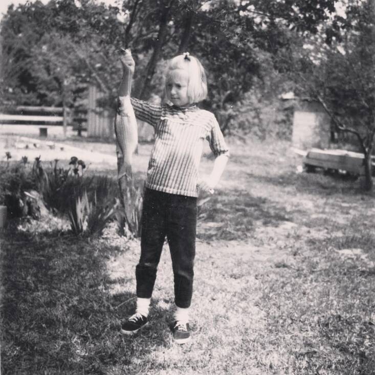 Christine, with her first ever catch, at her grandparents&#8217; lake house. Photograph courtesy of Christine Ten Eyck.