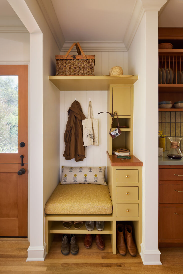 Butter yellow shows up all over this charming home, but we especially love it here in this little entryway storage nook. Photograph by Ye Rin Mok, from Color Connection: A Warm and Whimsical Remodel in Altadena, Los Angeles.