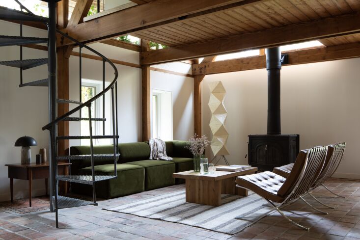 In a home of neutrals, a moss-colored sofa makes a statement. Photograph by Man Photography, courtesy of Takatina, from A Midcentury-Style \1980s House: The Takatina Take on an Upstate Hideaway.